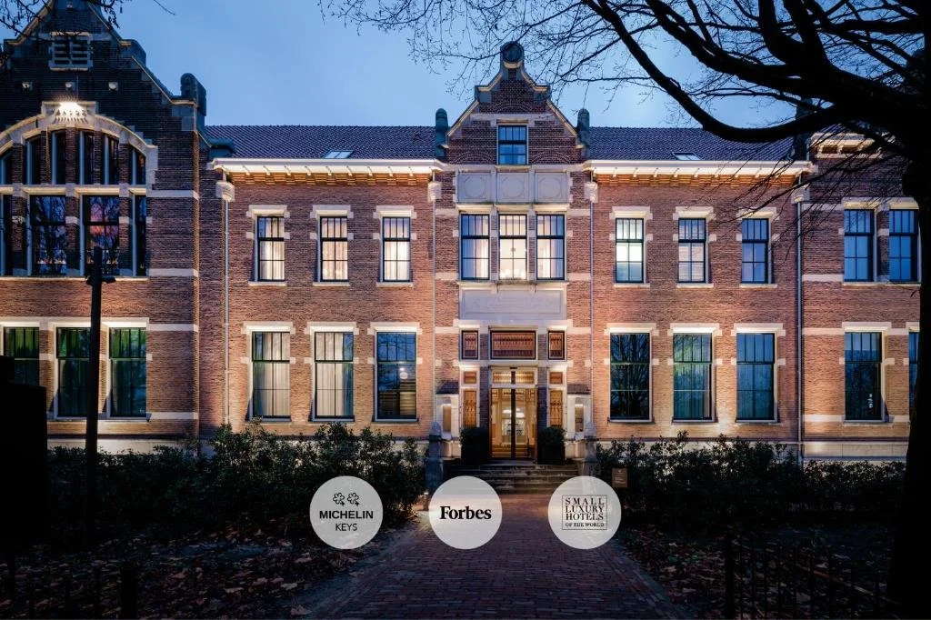 ein großes Backsteingebäude mit Schildern davor in der Unterkunft Pillows Grand Boutique Hotel Maurits at the Park - Small Luxury Hotels in Amsterdam