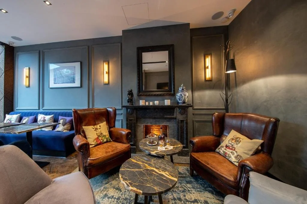 ein Wohnzimmer mit Ledersesseln und einem Kamin in der Unterkunft De Ware Jacob Boutique Hotel in Amsterdam