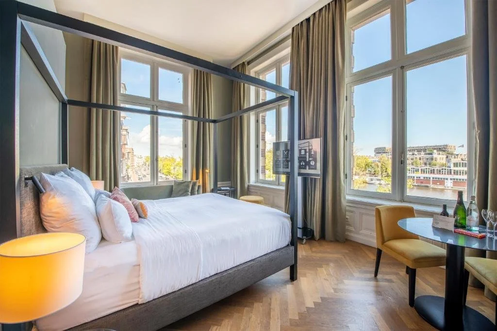 ein Hotelzimmer mit Bett, Schreibtisch und Fenstern in der Unterkunft Pestana Amsterdam Riverside in Amsterdam