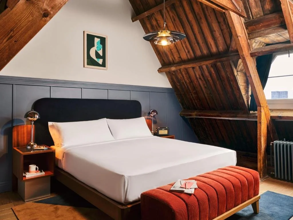 ein Schlafzimmer mit einem weißen Bett und einem roten Hocker in der Unterkunft The Hoxton, Lloyd Amsterdam in Amsterdam