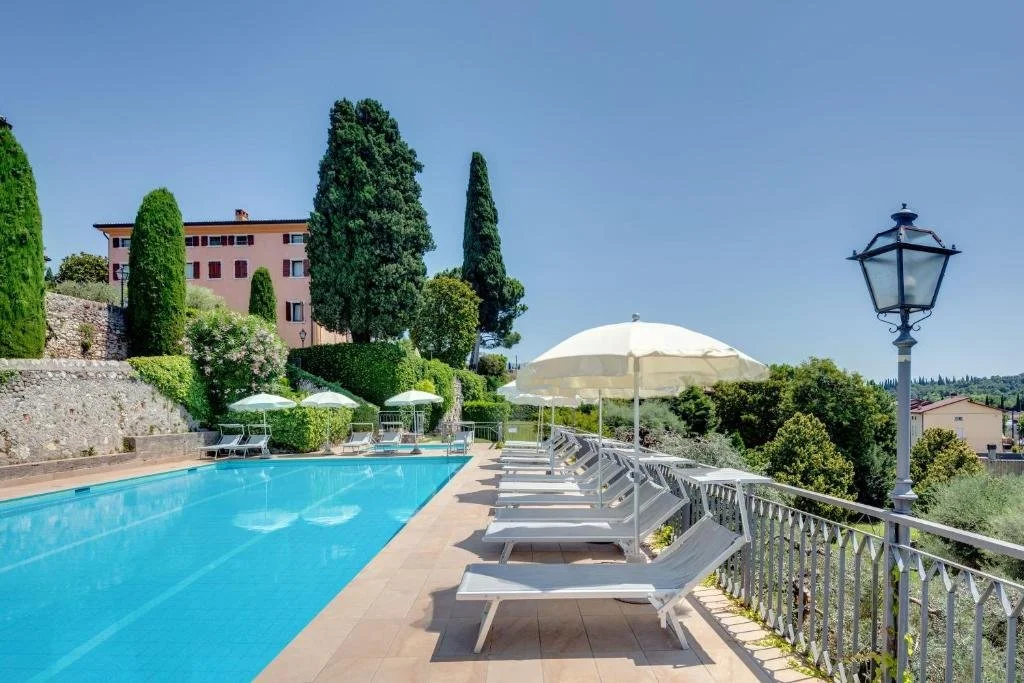 ein Swimmingpool mit Liegestühlen und einem Sonnenschirm in der Unterkunft Residence La Filanda in Costermano sul Garda