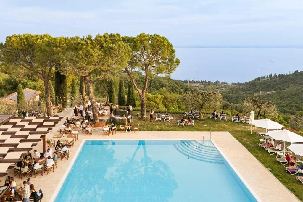 Eine Gruppe von Menschen sitzt um ein Schwimmbecken herum in der Unterkunft Residence San Michele in Costermano sul Garda