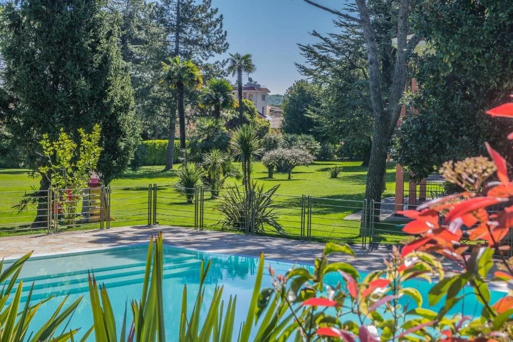 ein Garten mit Schwimmbad und Park in der Unterkunft Residence Oasi in Manerba del Garda