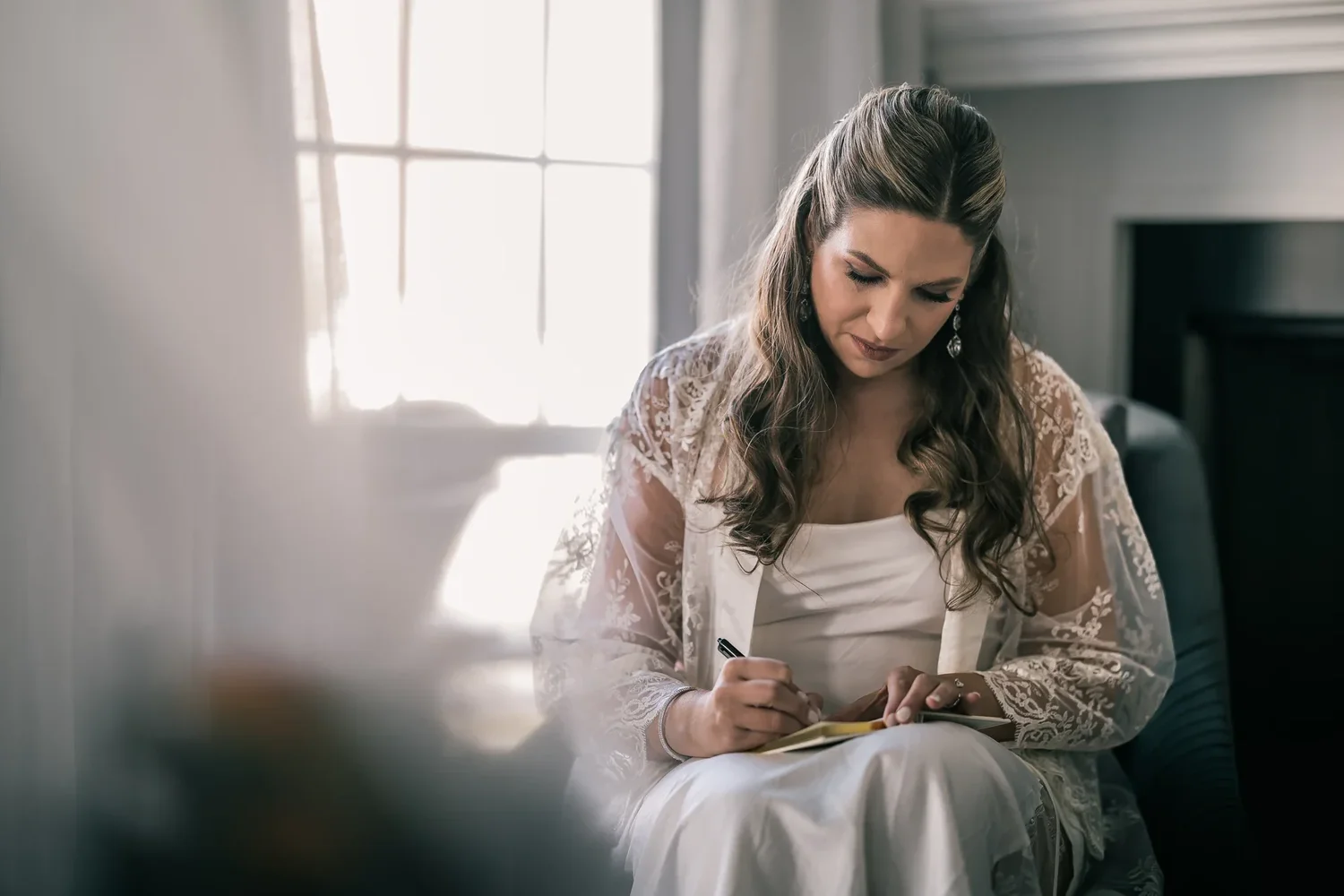 Charissa writing a letter to Andrew in window light while getting ready at Windham Manor
