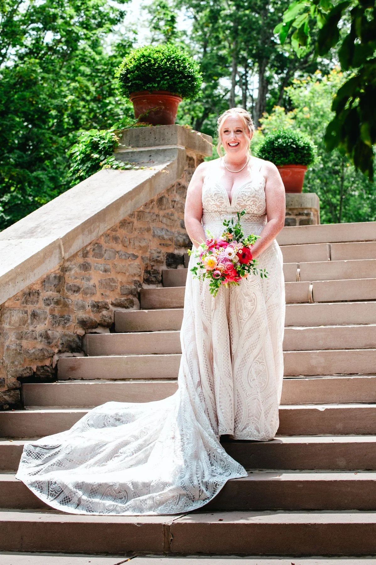 Amanda holding her bouquet on outdoor stone steps at The Otesaga