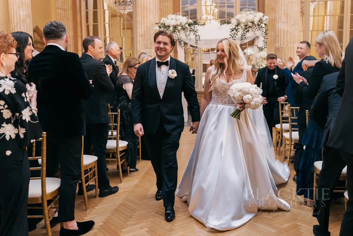 Guests cheering as Catie and Brad walk back up the aisle at Marriott Syracuse Downtown