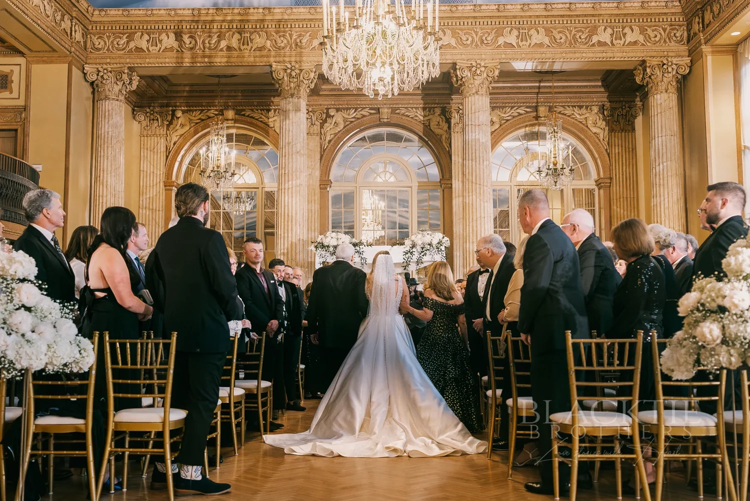 Wedding ceremony aisle with gold chairs and crystal chandeliers at Marriott Syracuse Downtown