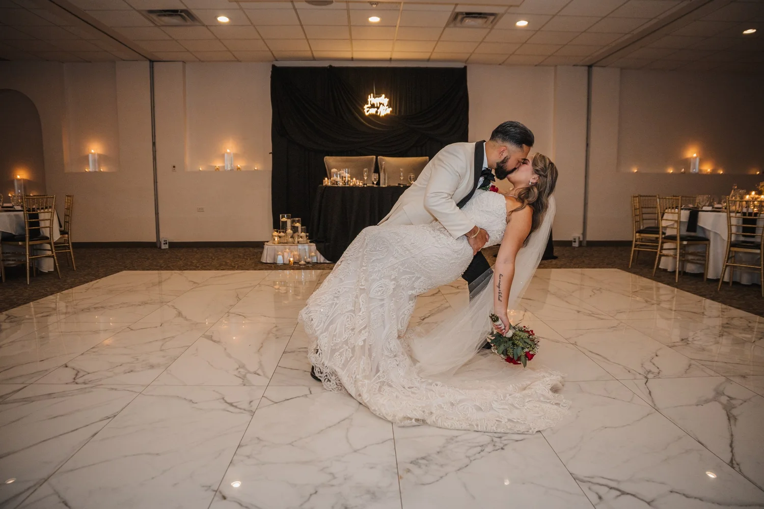 Mitchell dipping Alice for a kiss in the middle of the empty marble-style dance floor, candles along the walls