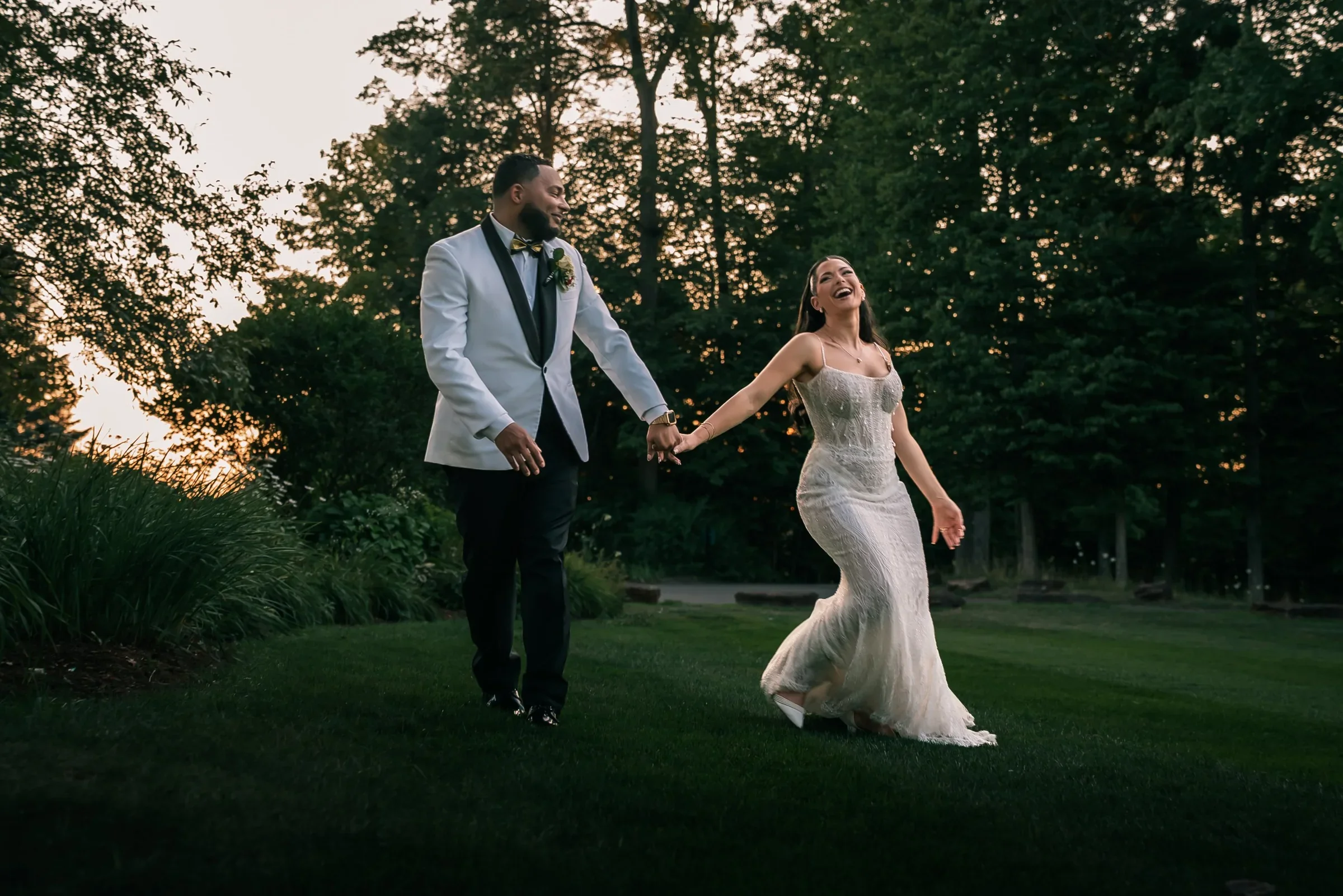 Vanessa laughing as she leads Trevor across the lawn by the hand at sunset