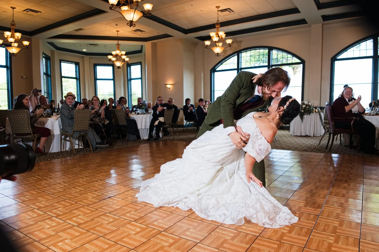 Jason dips Marseille during their first dance in the Meritage Ballroom, guests watching from their tables under the chandeliers