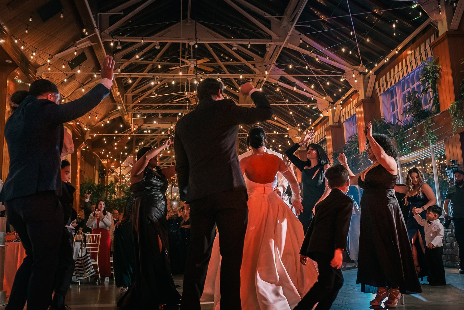 Guests surround Patricia and Joshua on the dance floor beneath the lights at The Somerley.