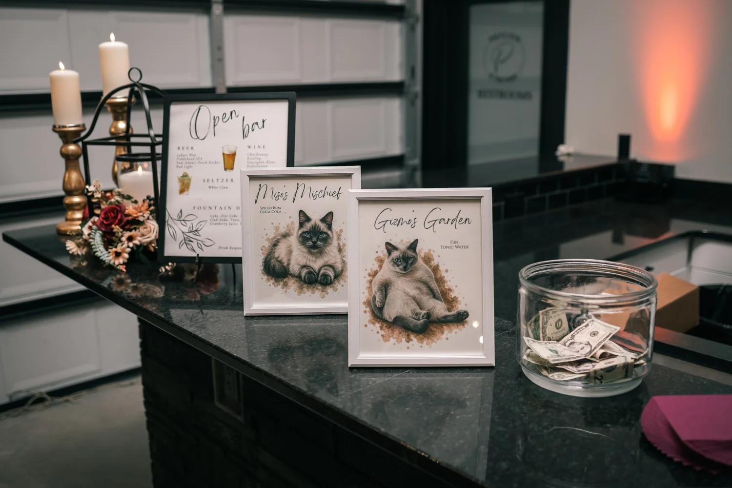 Framed bar signs featuring drawings of the couple’s cats, beside candles on the bar