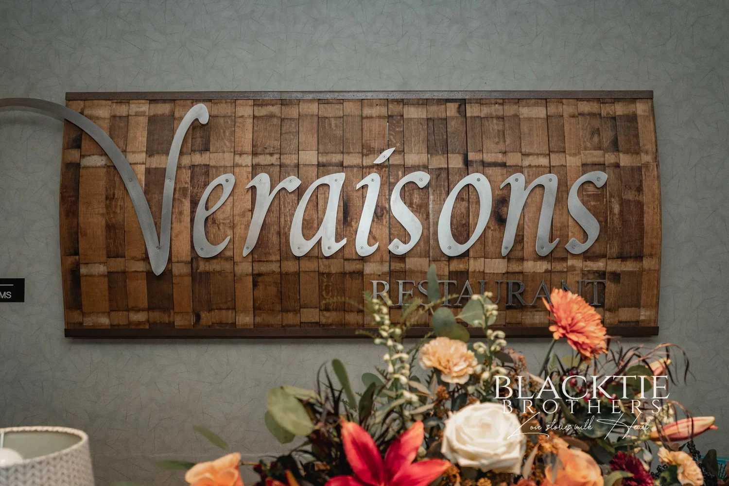 The carved Veraisons Restaurant sign at Glenora Wine Cellars with autumn flowers arranged below it