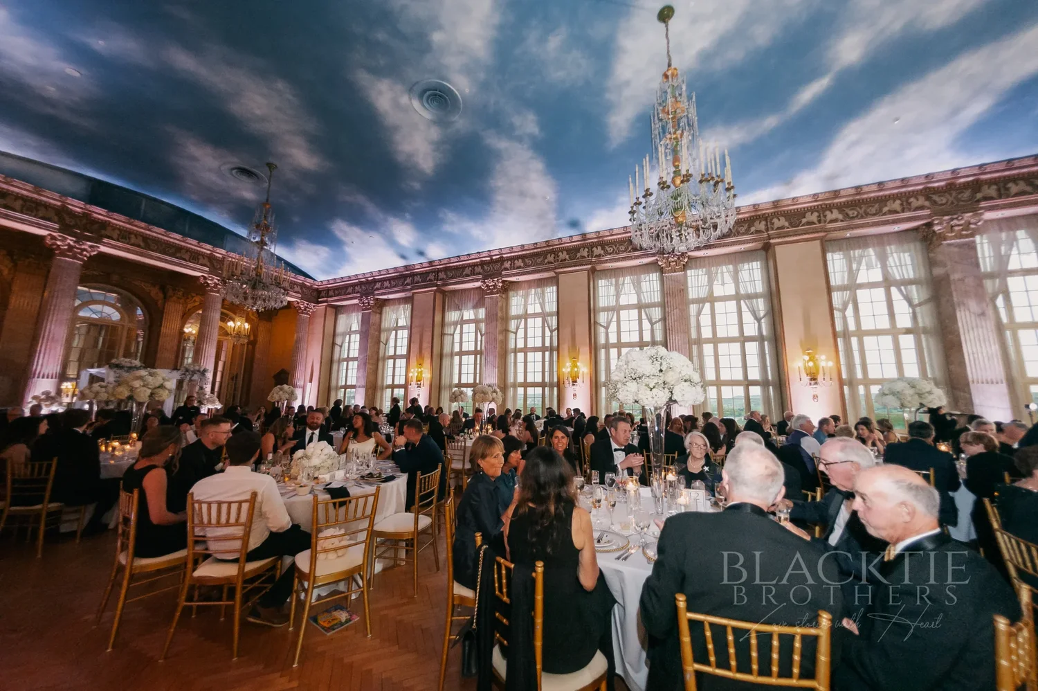 Wedding reception dinner beneath a painted sky ceiling and crystal chandeliers at Marriott Syracuse Downtown
