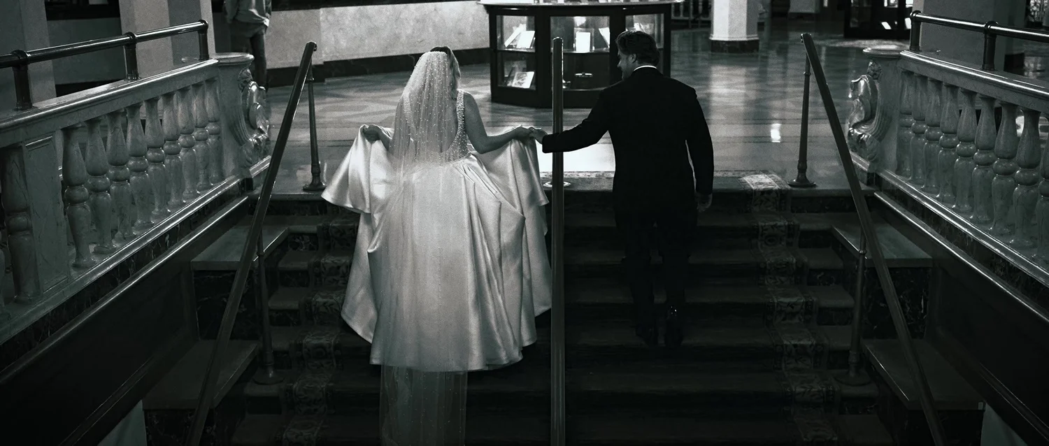 Catie and Brad holding hands on an ornate staircase at Hotel Syracuse