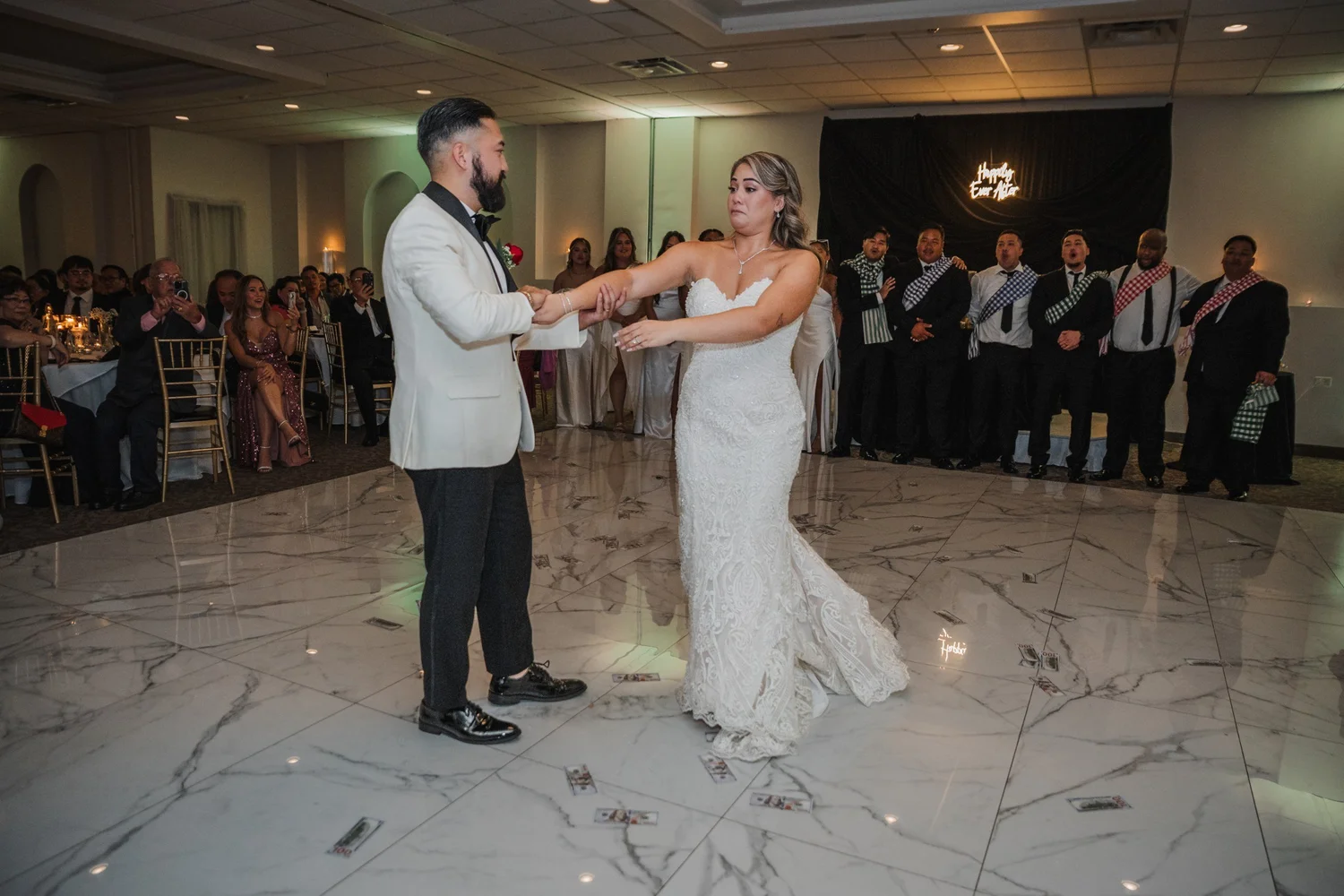 Alice and Mitchell’s first dance on the ballroom floor, their wedding party lined up behind them