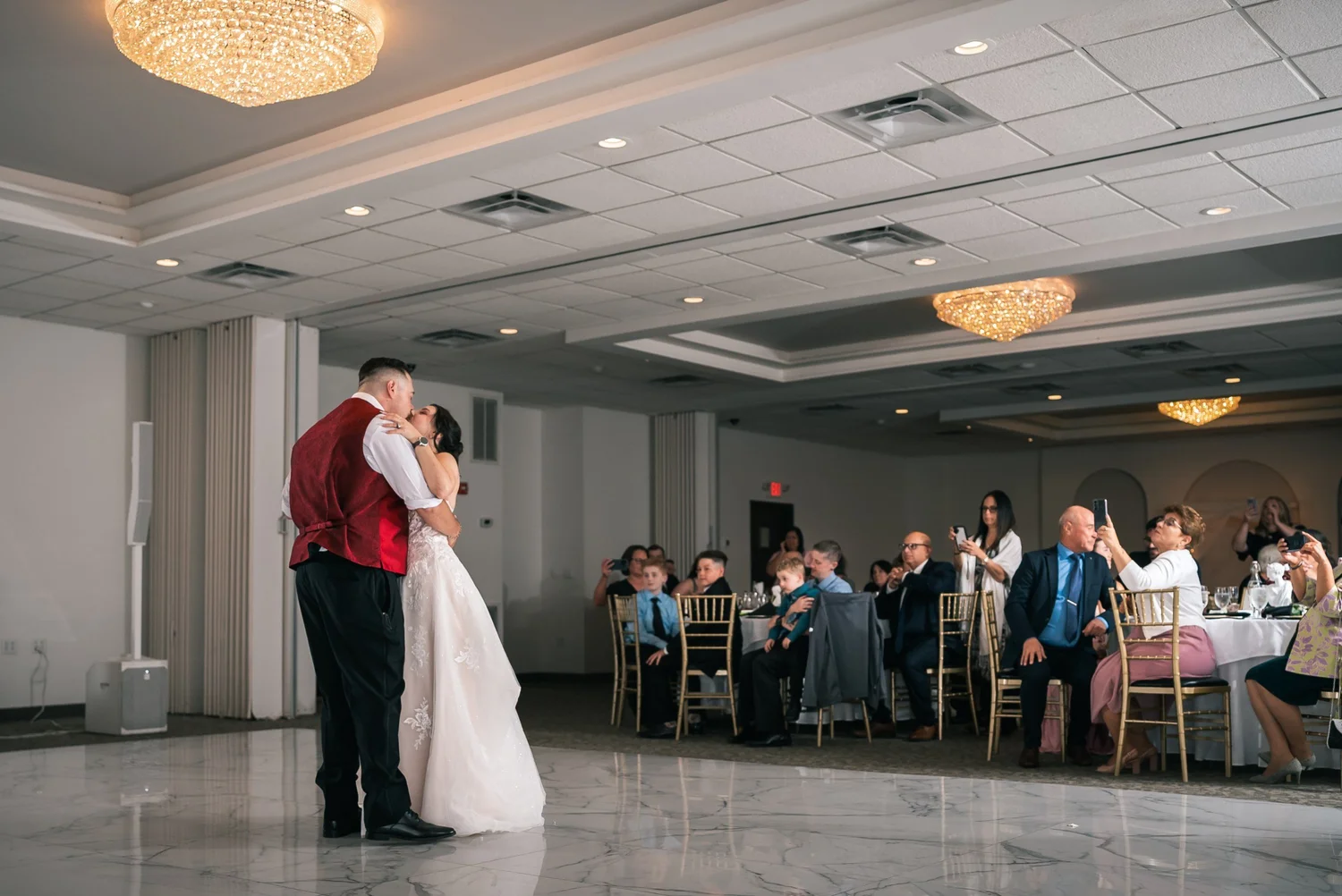 Laura and Dante’s first dance on the marble-style floor of the ballroom, guests watching from their tables under the chandeliers