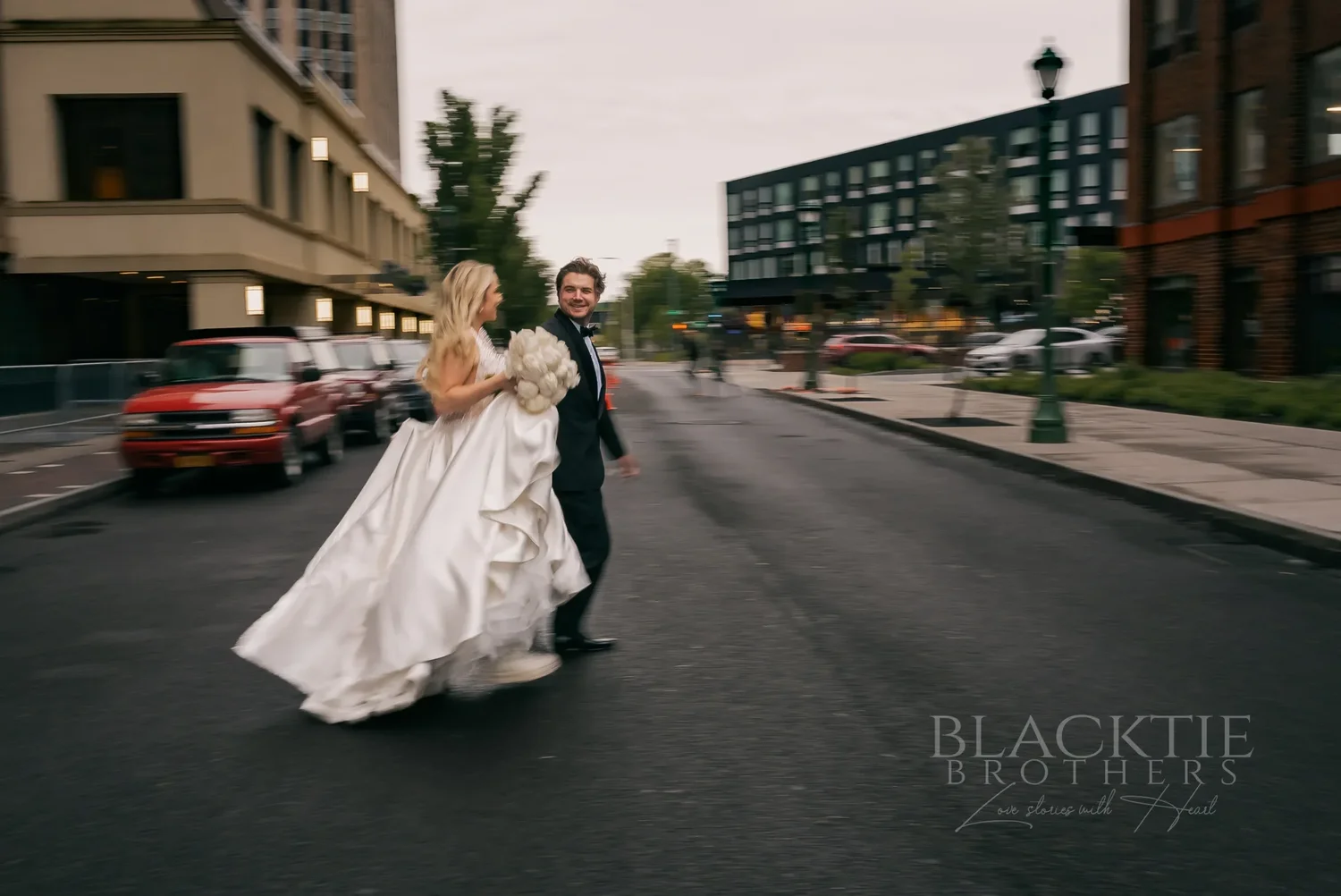 Catie and Brad running hand in hand down a downtown Syracuse street