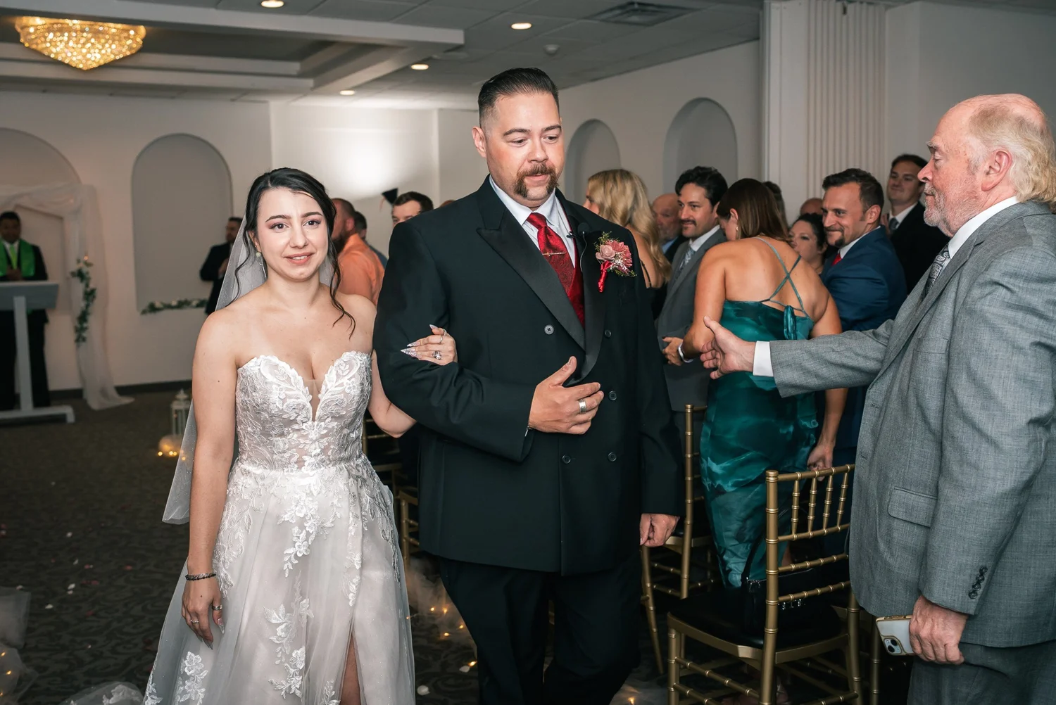 Laura and Dante walking back up the aisle arm in arm as guests stand and smile