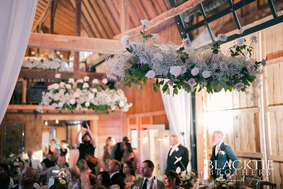 A hanging floral installation suspended from the barn beams at LedgeRock during the reception.