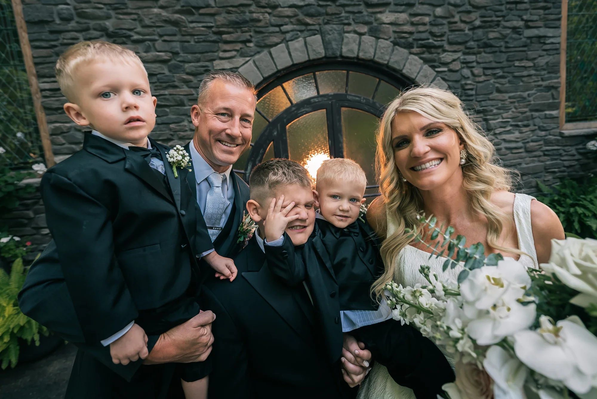 Couple with their sons in front of the arched stone window of the chapel at LedgeRock.