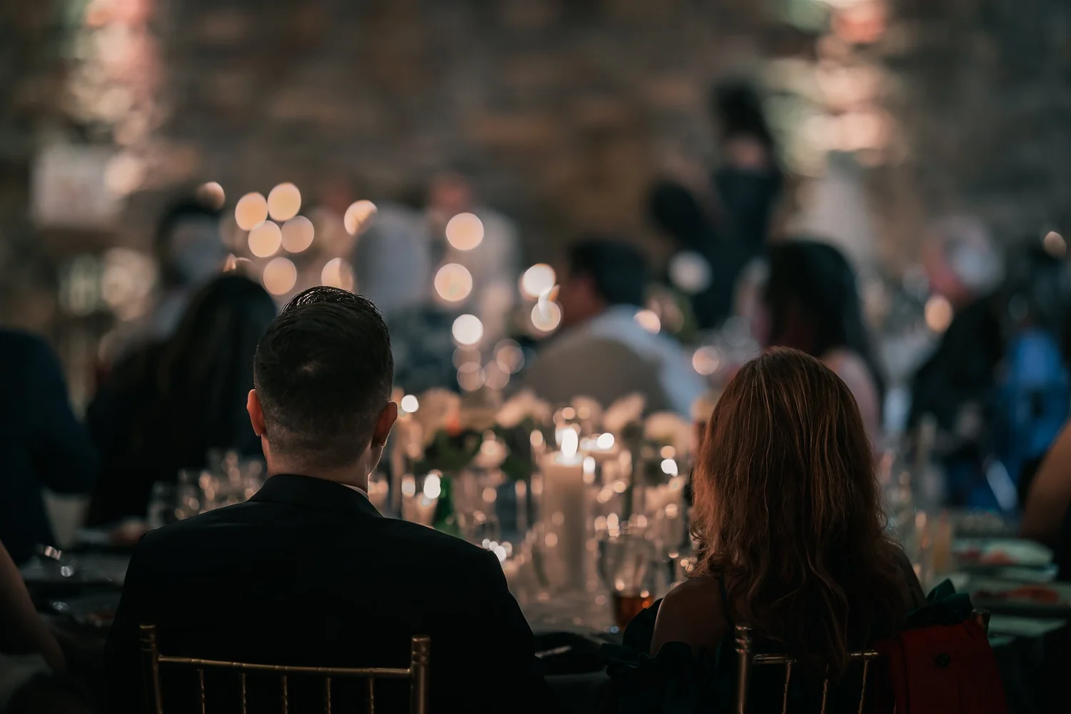 Seated guests look toward the candlelit reception tables inside The Somerley at Fox Hollow.