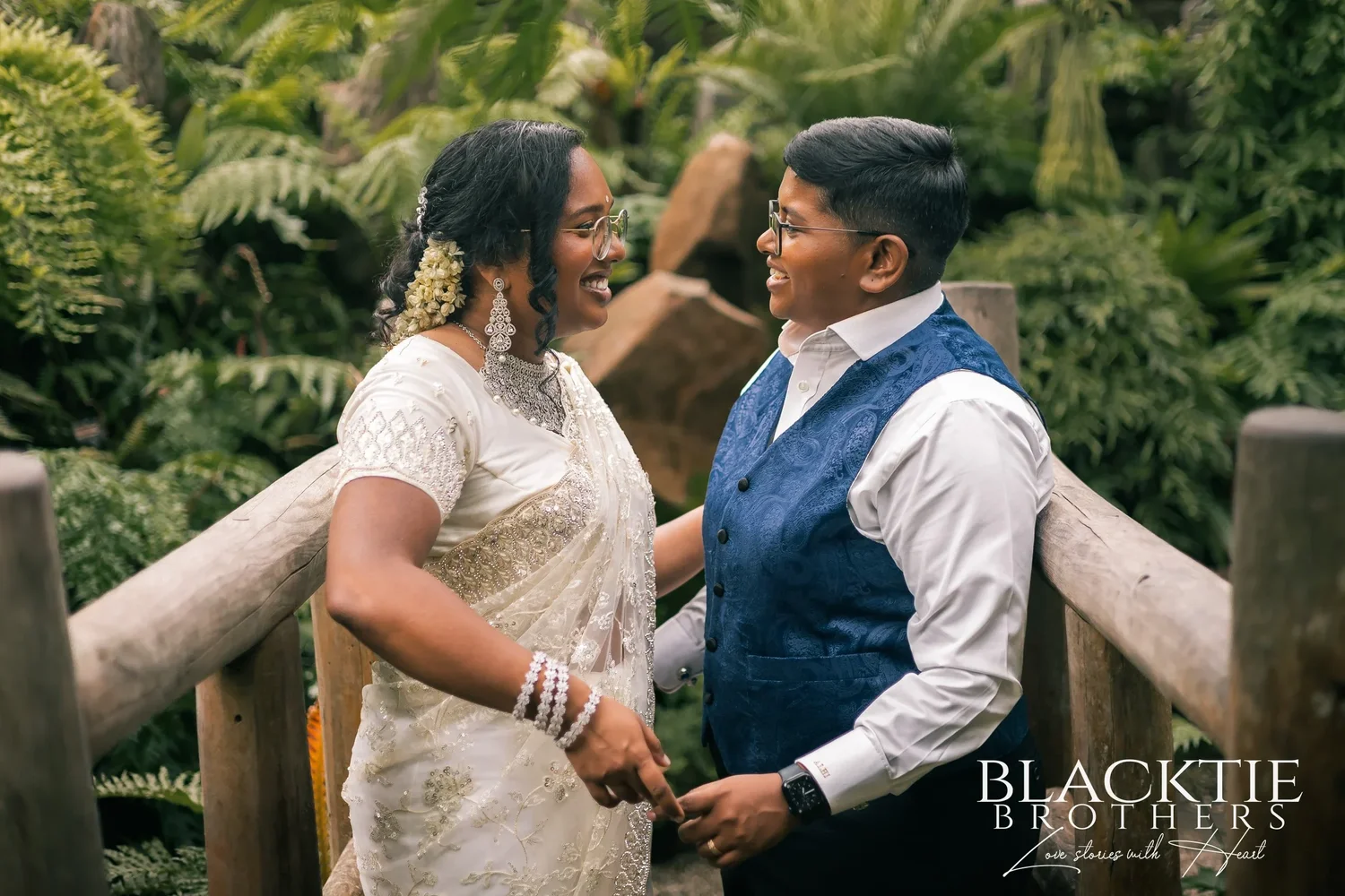 Hima and Alina holding each other and smiling on the wooden bridge in the Fernery, surrounded by ferns