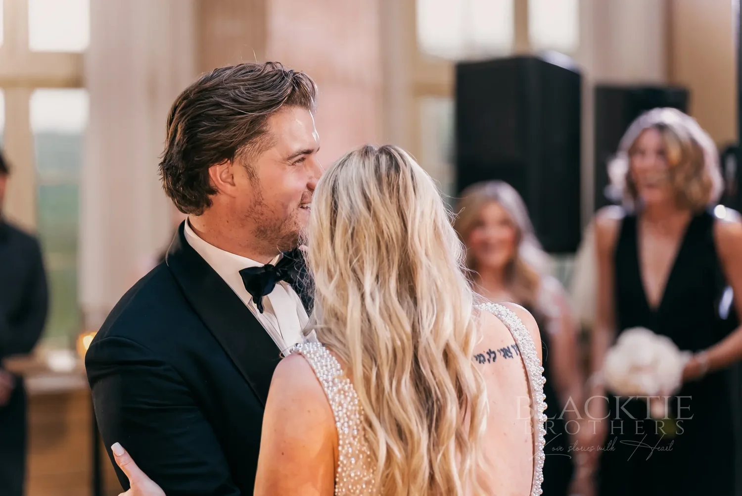 Catie and Brad close together on the dance floor with guests around them at Marriott Syracuse Downtown