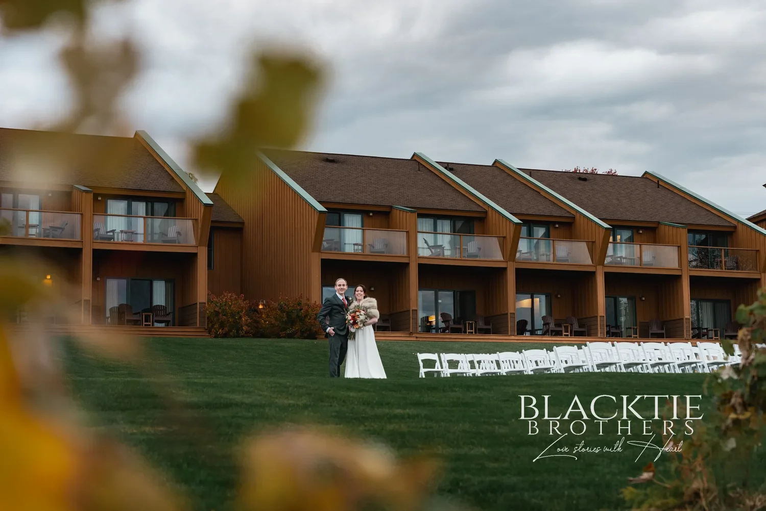 Anya and Gabe walking on the lawn in front of The Inn at Glenora, with the white ceremony chairs still in their rows