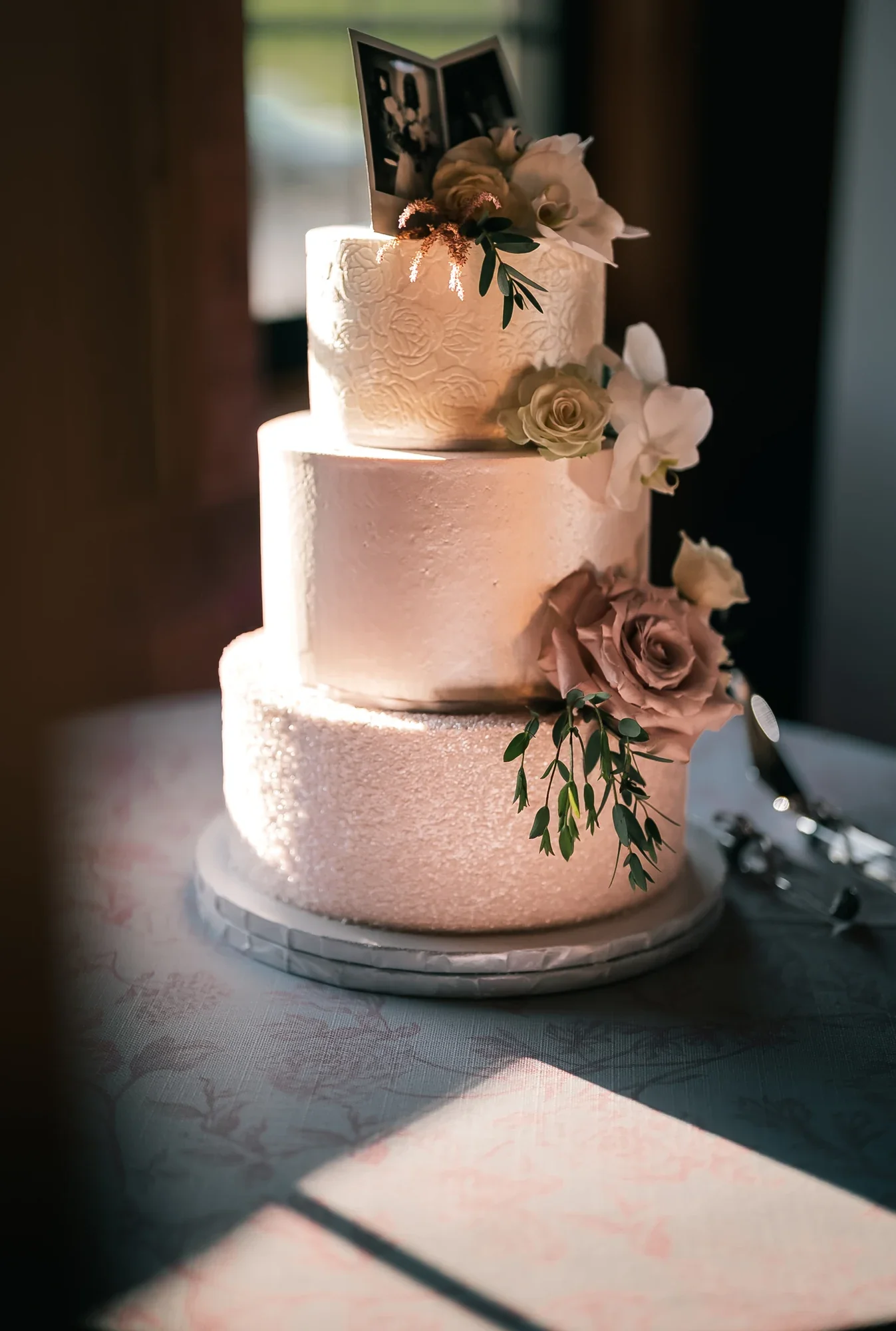 Tiered wedding cake in window light at the LedgeRock barn.