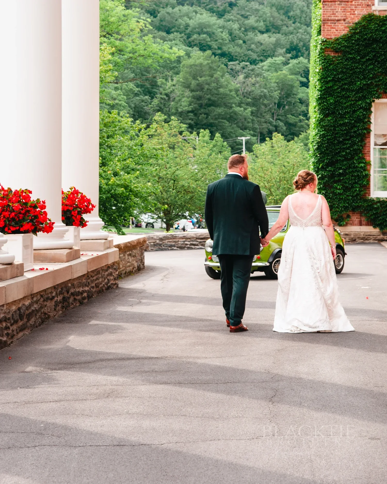 Amanda and Chris walking past the white columns of The Otesaga Resort Hotel