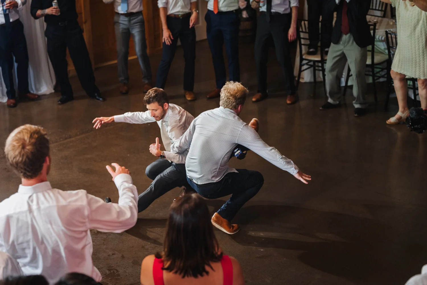 Two guests dancing low to the floor while others watch and cheer