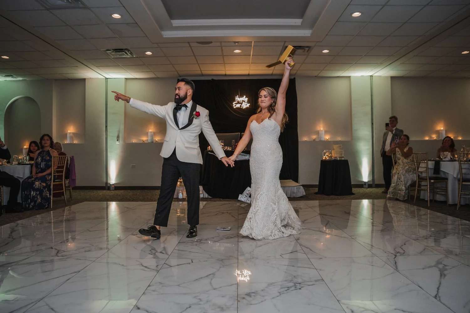 Alice and Mitchell dancing into the reception, Alice with one arm raised, green uplighting along the walls
