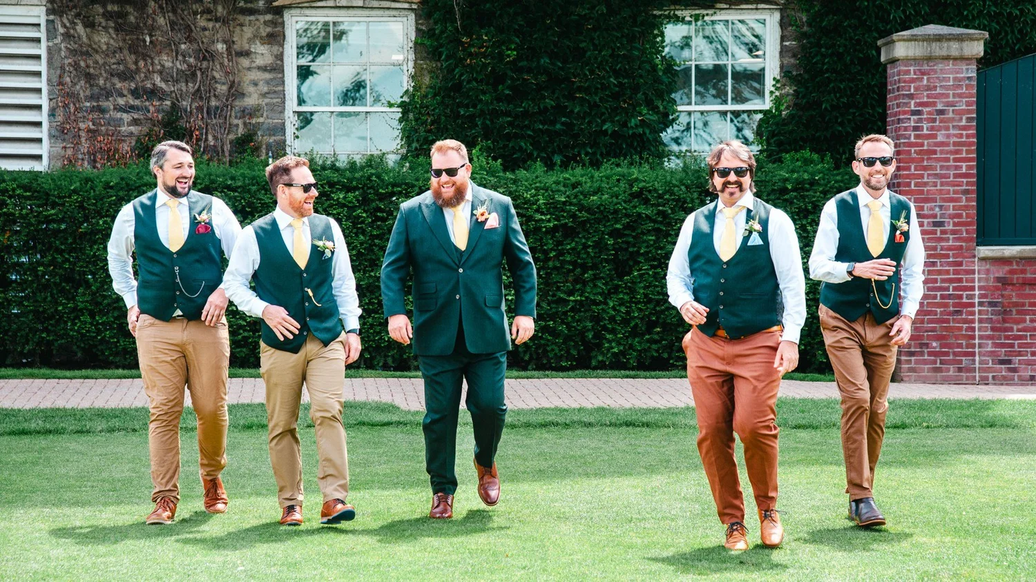 Groomsmen in green waistcoats and tan trousers on The Otesaga lawn