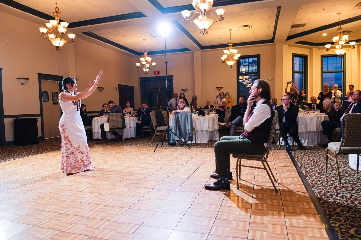 Marseille, now in a floral dress, dancing for Jason as he watches from a chair on the Meritage Ballroom floor