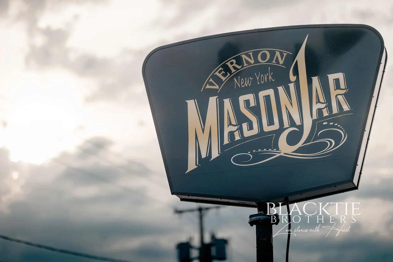 The Mason Jar's roadside sign, reading Vernon New York Mason Jar, against a bright cloudy sky