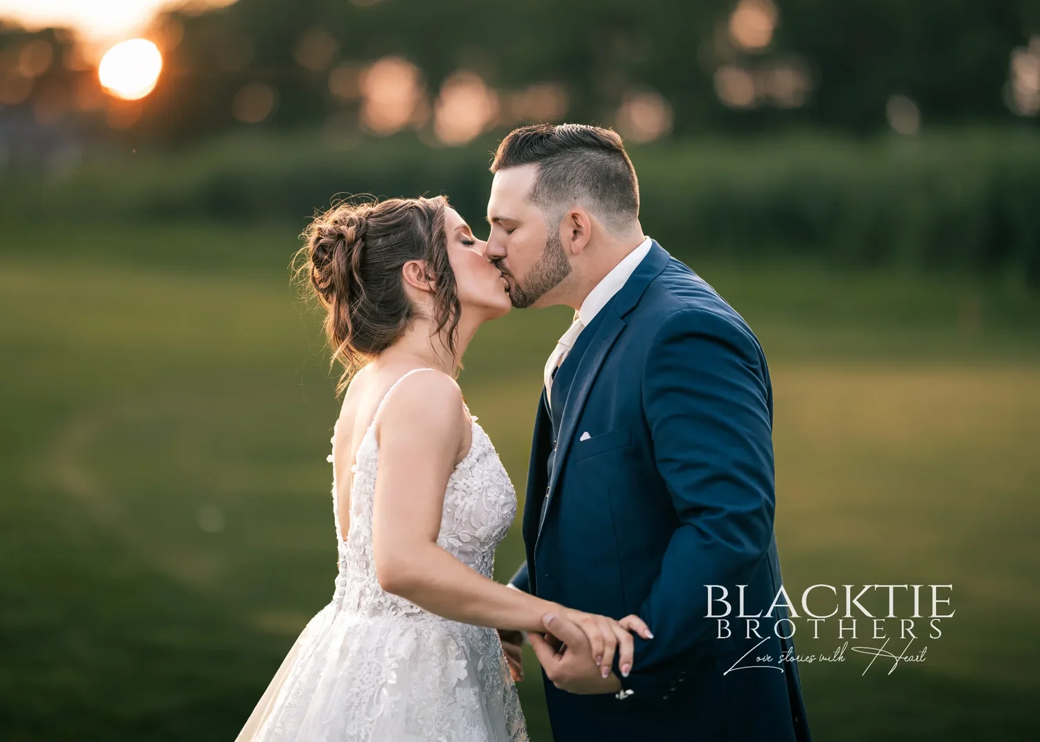 Taylor and Jake kissing on the fairway with the setting sun flaring through the trees behind them