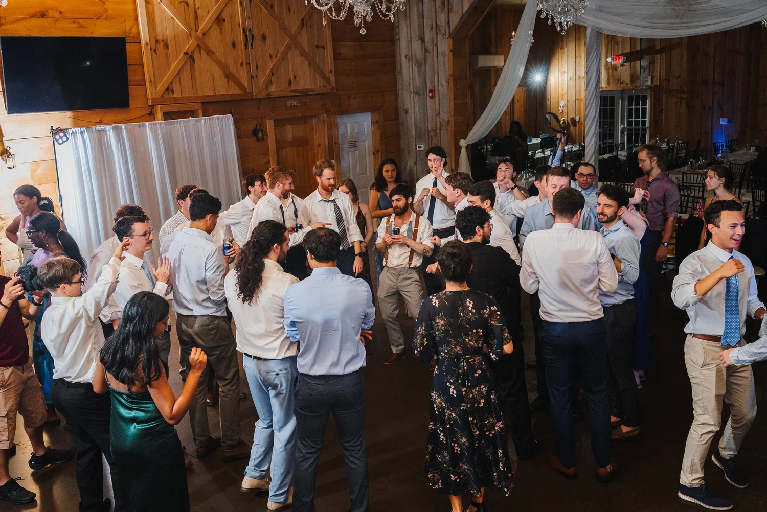 A full dance floor under the barn’s chandeliers and draped fabric, seen from above