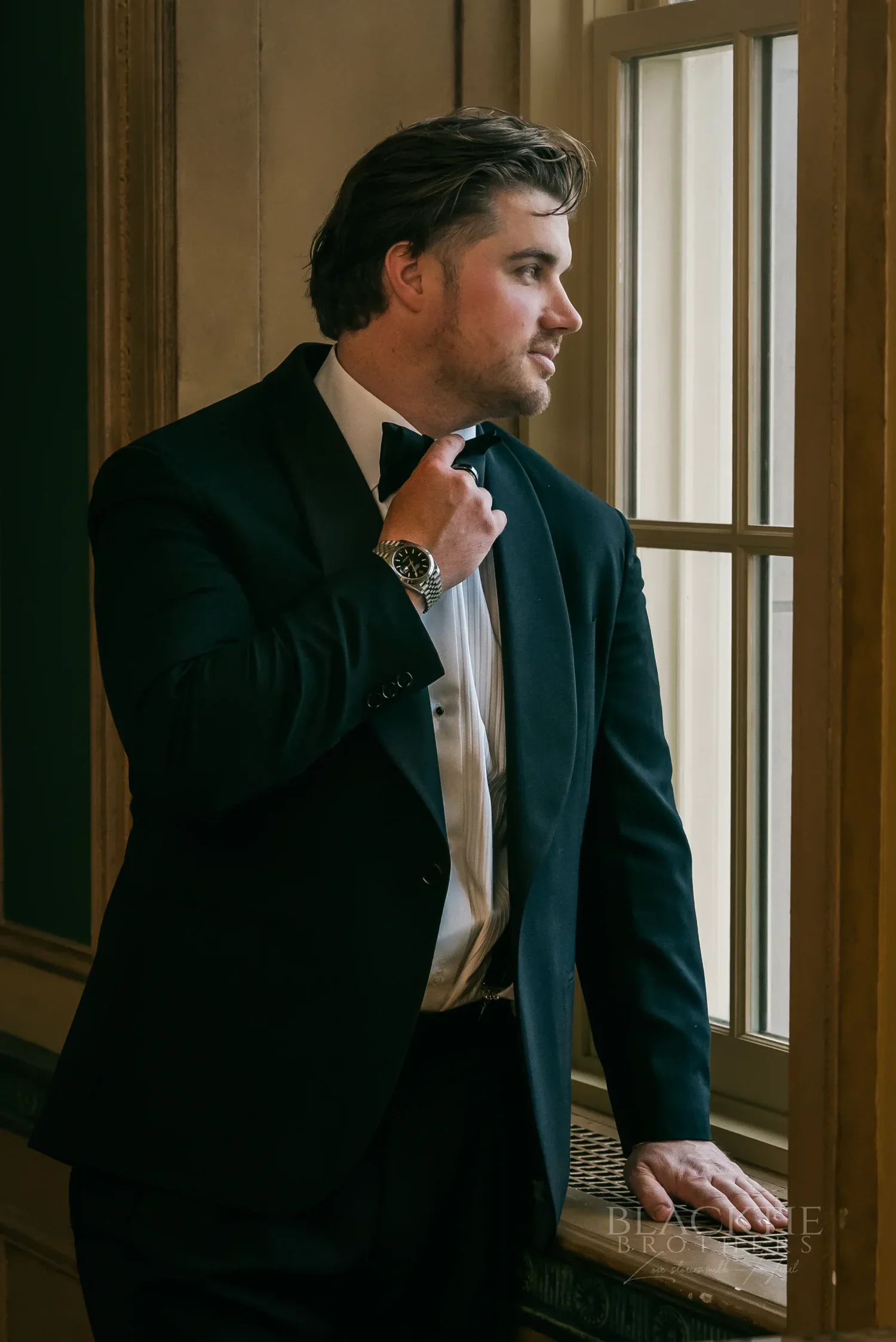 Brad in his tuxedo by a tall window before the ceremony at Marriott Syracuse Downtown