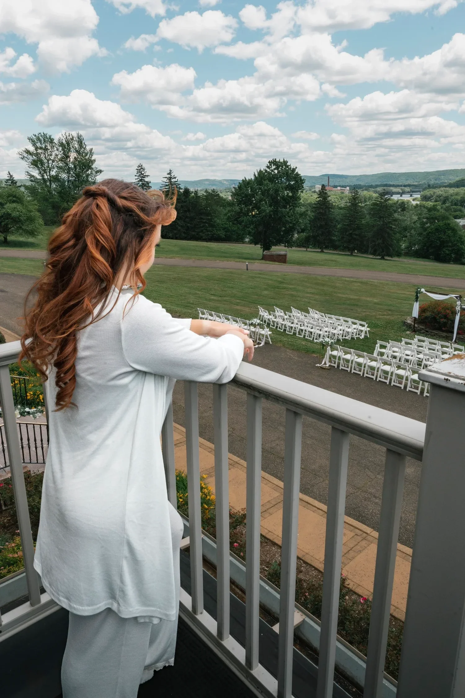 Danielle on the balcony at Traditions at the Glen, looking down at the white ceremony chairs set out on the lawn