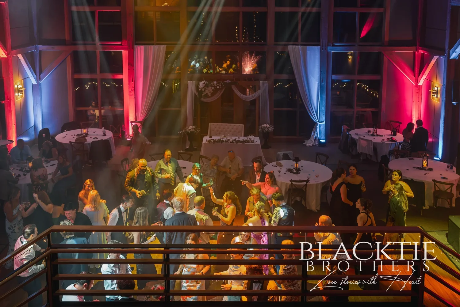 The reception at Allyn Lodge seen from the mezzanine, with red and blue uplighting on the timber frame.
