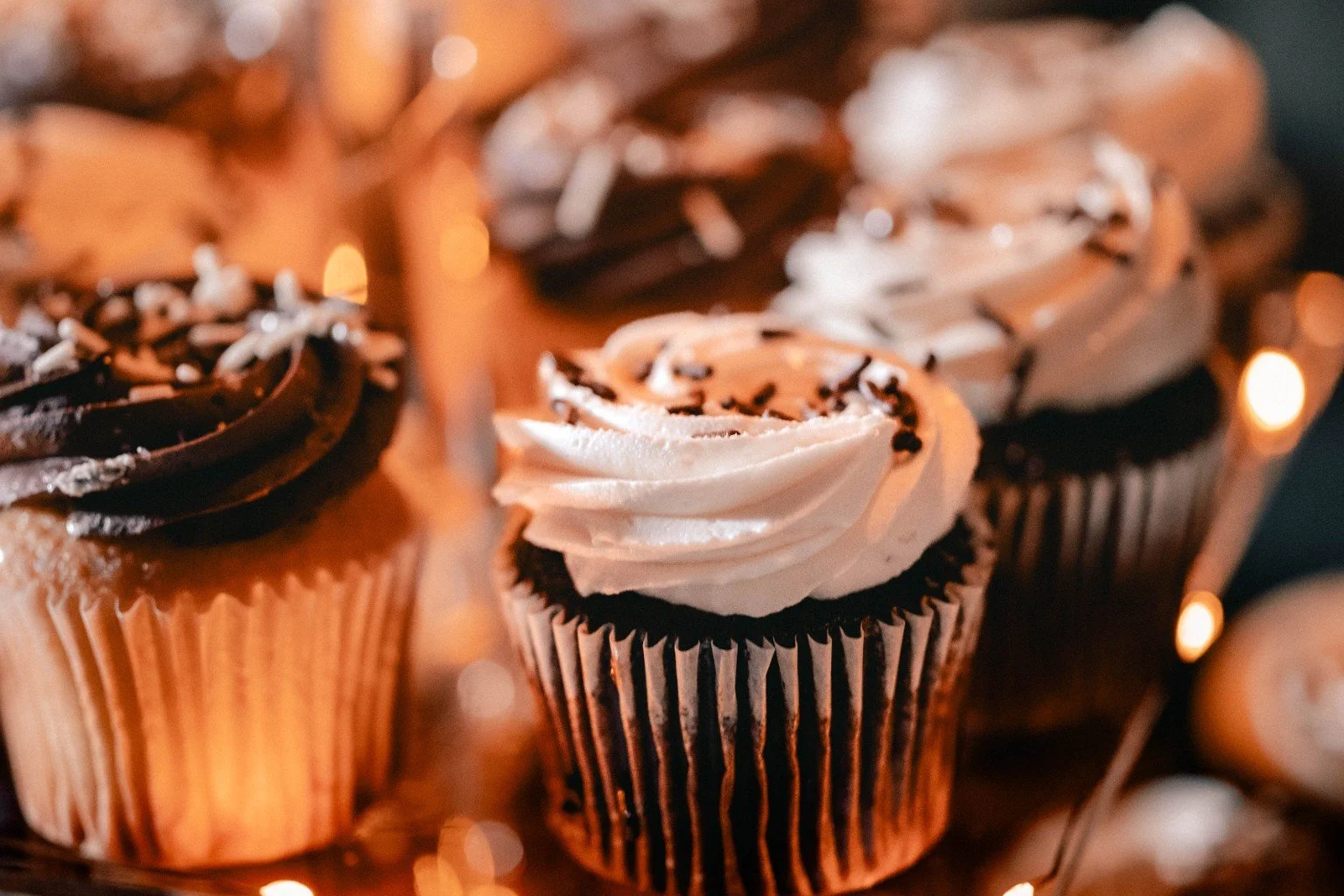White and chocolate frosted cupcakes on a warmly lit wedding dessert display.