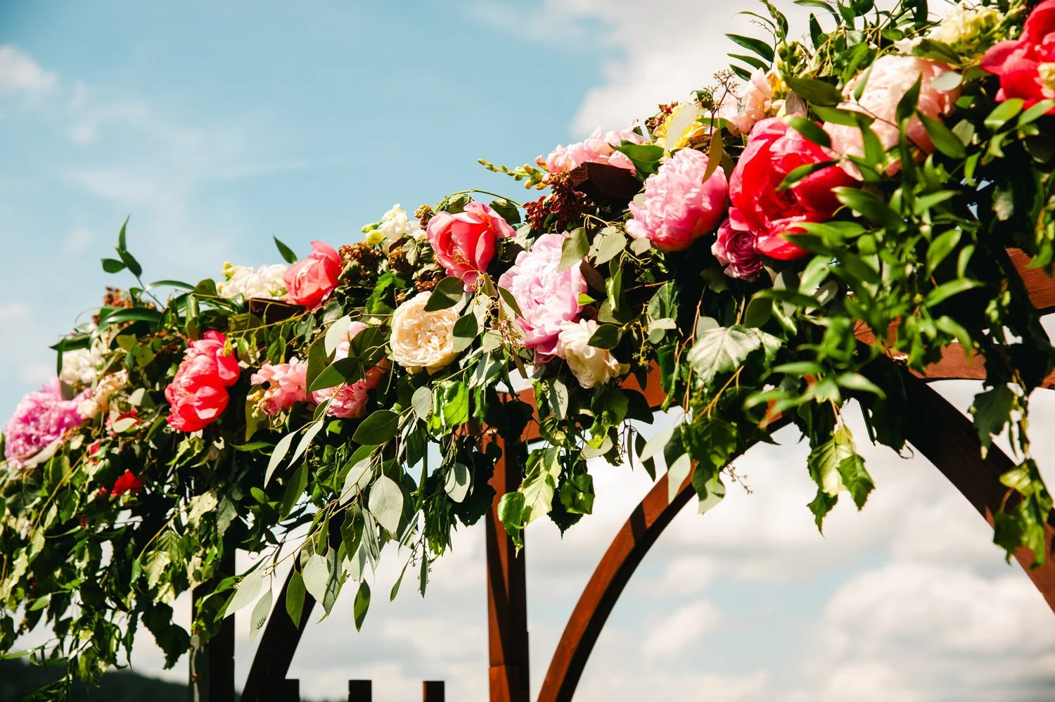 Red and pink flowers on the outdoor wedding arbor at The Otesaga
