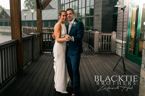 A couple on the deck at Allyn Lodge with the lodge behind them.