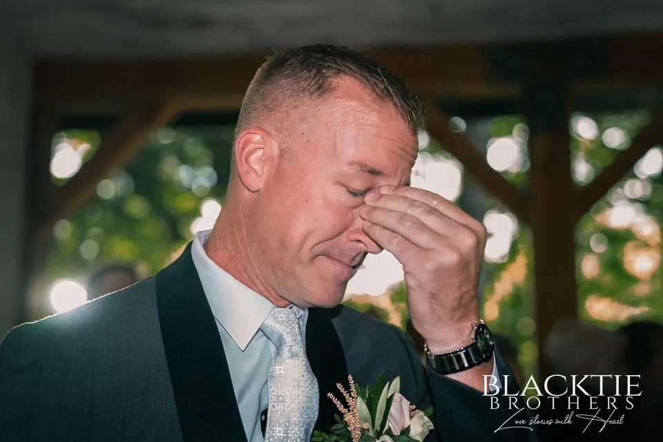 The groom wipes away tears at the altar of the Chapel in the Woods at Graceful Gatherings at LedgeRock as the bride approaches.