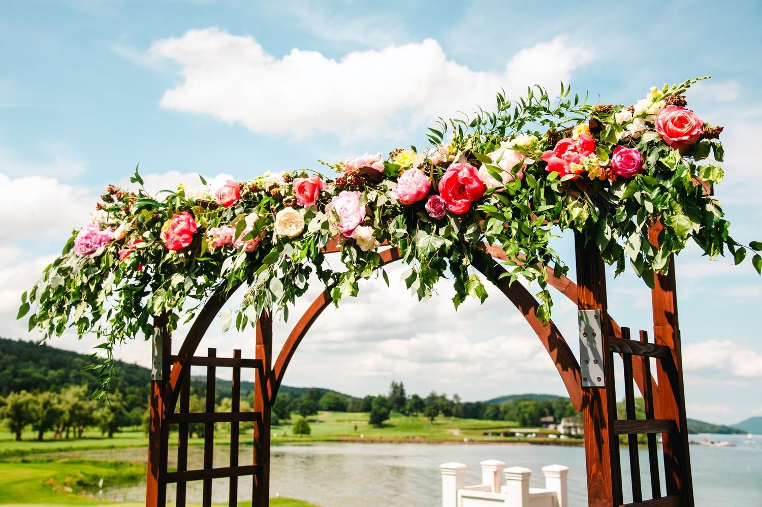 Outdoor ceremony arbor with flowers and Otsego Lake beyond