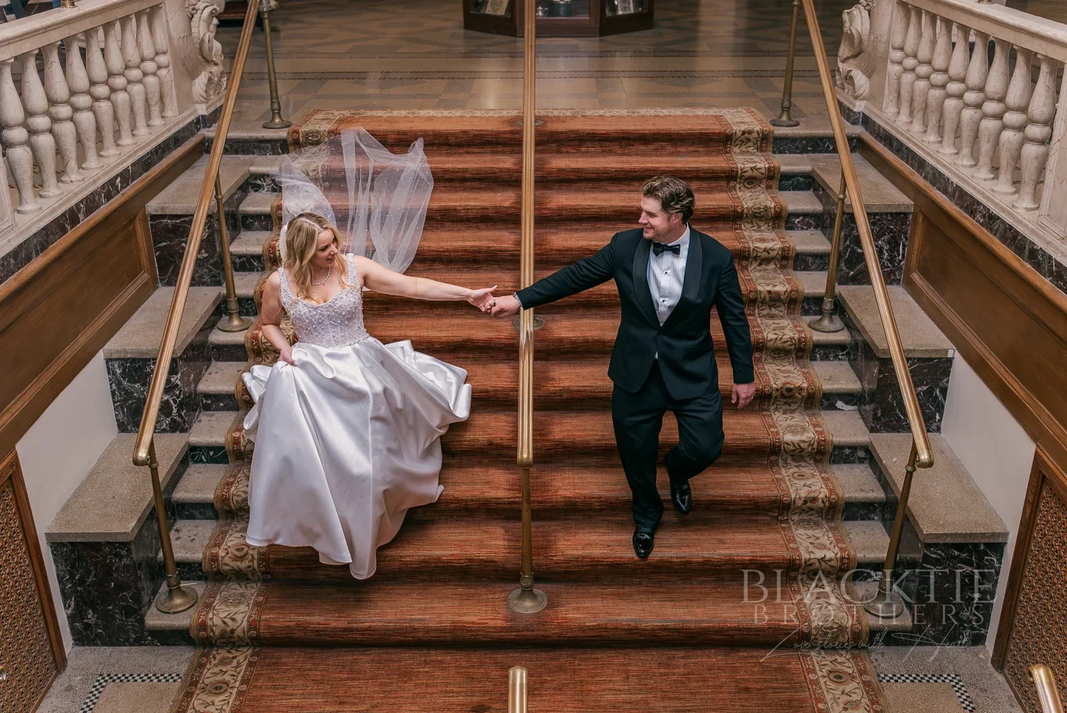Catie and Brad on the red-carpeted grand staircase at Marriott Syracuse Downtown