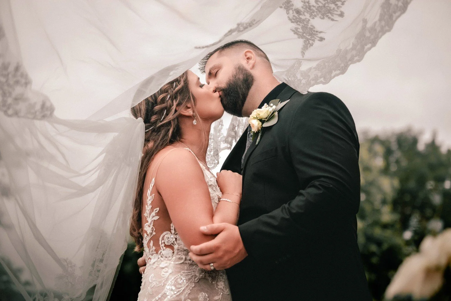 Joelle and Louie kiss beneath her lace-edged veil during their wedding portraits.