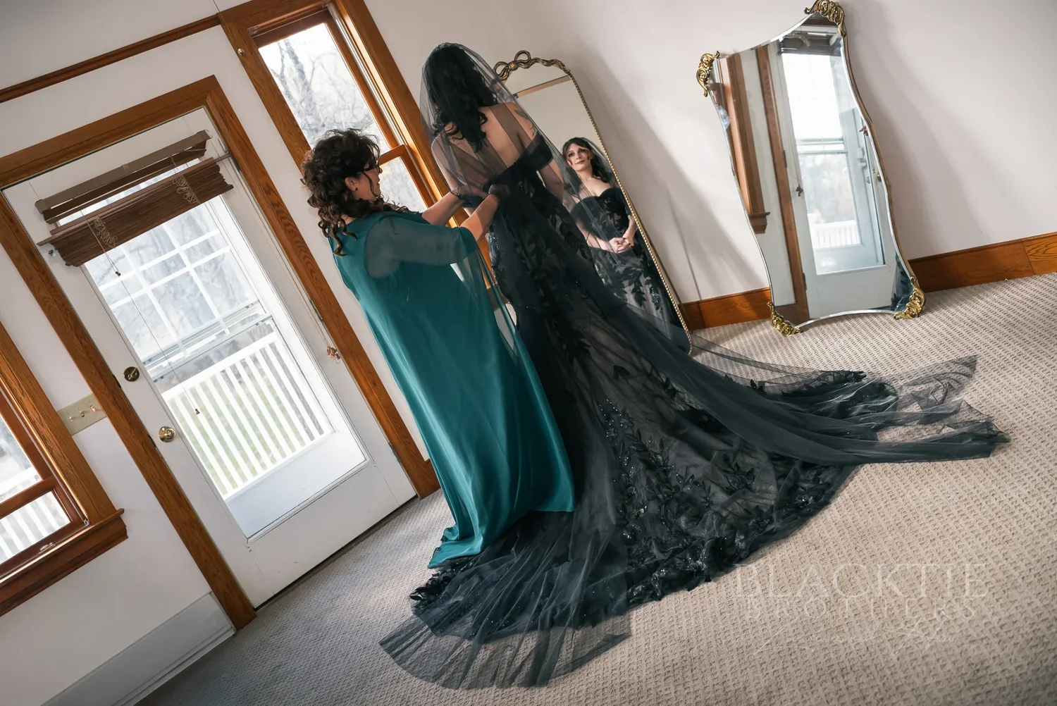 Maddy in her black lace wedding gown standing in soft window light while getting ready at Stratton Creek Inn