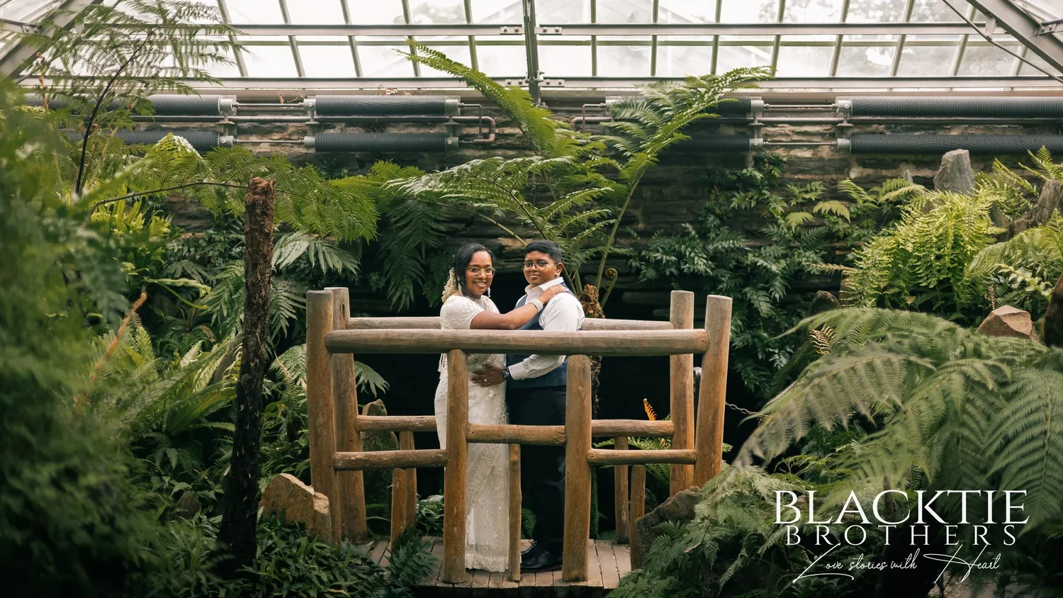 Inside the Fernery at Morris Arboretum: a glass roof over a deep bed of ferns, with Hima and Alina standing on a small wooden bridge in the middle